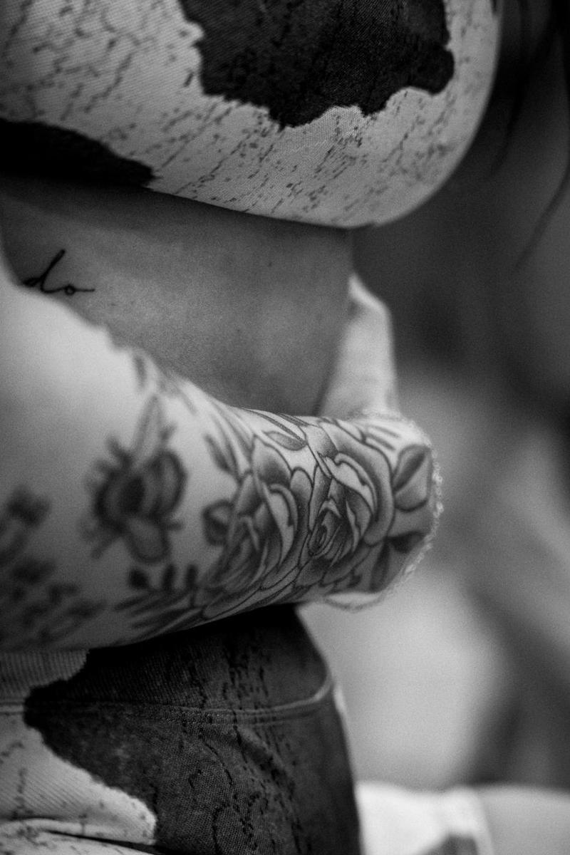 Black and white close-up of a rose tattoo on a forearm