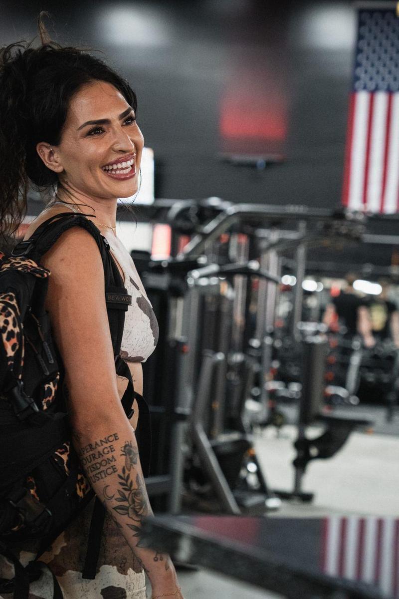 Female athlete smiling with her gym bag, an American flag behind her