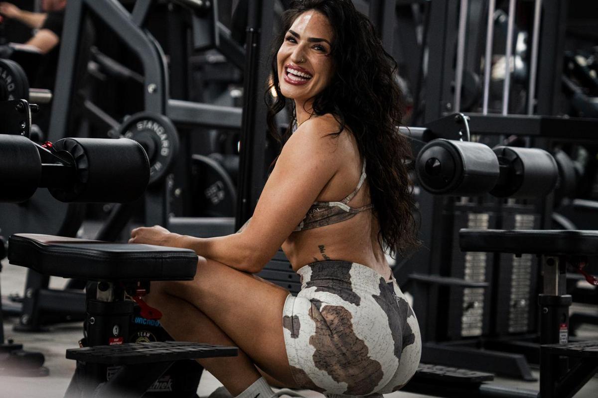 Female athlete laughing beside a bench in a gym full of machines