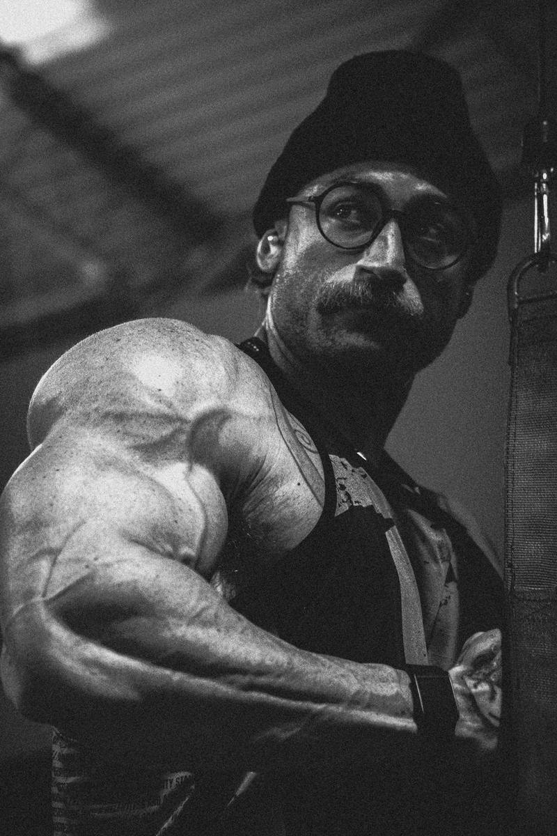Black and white close-up of a flexed arm, the athlete looking over his shoulder