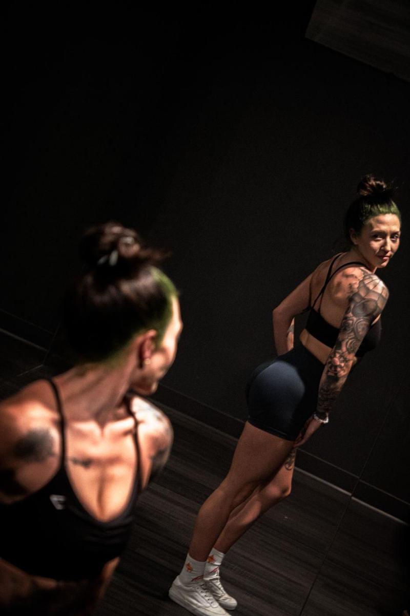 Tattooed athlete glancing back over her shoulder at her reflection