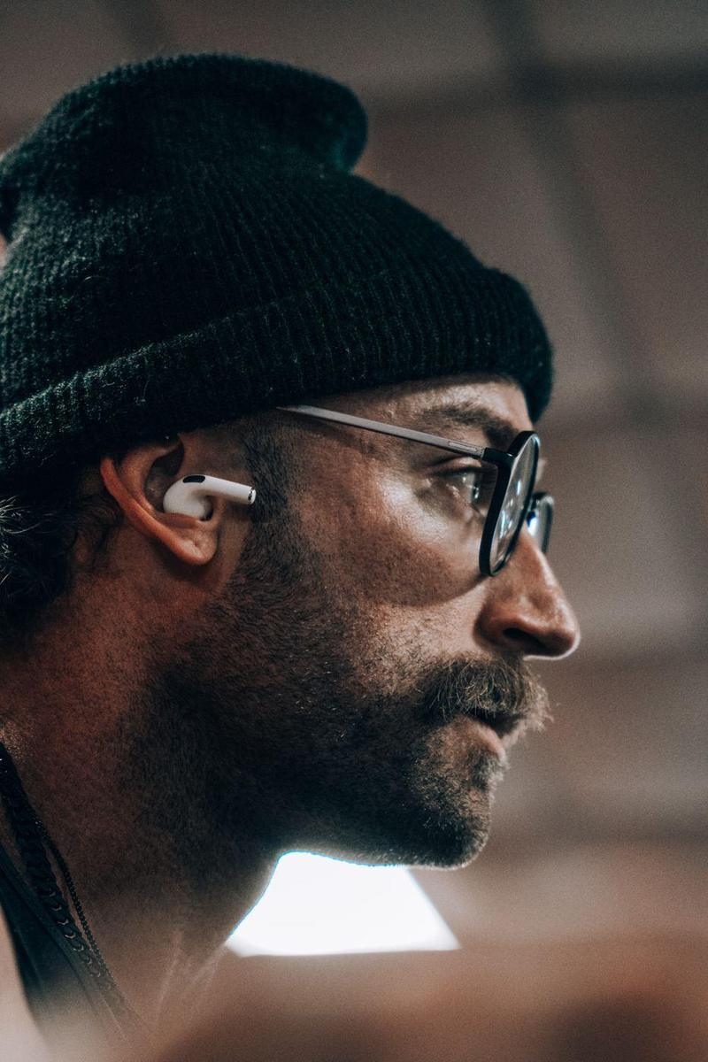 Close profile portrait of a man in a beanie and round glasses